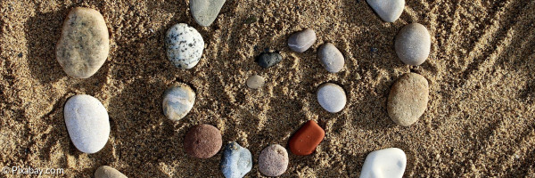 Aus Steinen gelegte Spirale auf Sand